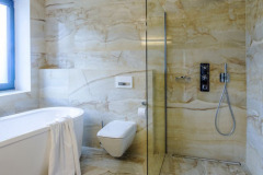 Koupelna je obložena přírodním leštěným mramorem. Vzhledem k výrazné kresbě obkladu a v zájmu zachování designové jednoty a čistoty je vybavení koupelny striktně minimalistické