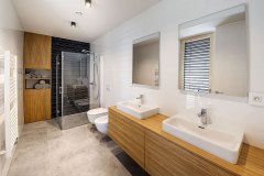 Kombinace olejovaného dřeva a šedé dlažby prochází celým interiérem včetně koupelen