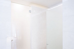 Interiér koupelny umístěné v kubické vestavbě v zadní části přízemí domu. Nahoře je vidět střešní okno, které do vestavby přivádí denní světlo