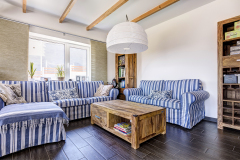 Obývací pokoj je vybaven masivním dřevěným nábytkem. Dřevěné stropní trámy slouží k doladění atmosféry